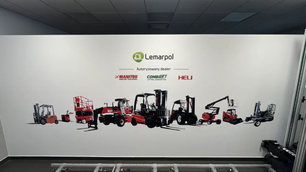 Druk ścienny przedstawiający logo firmy Lemarpol oraz maszyny przeładunkowe na ścianie hali firmowej.